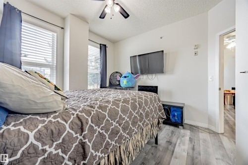 Bedroom featuring light wood-style flooring, a textured ceiling, and a ceiling fan - 132 6220 134 Avenue, Edmonton, AB - Indoor Photo Showing Bedroom