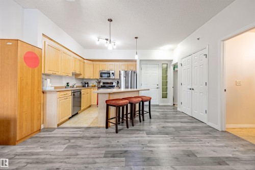 Kitchen featuring light wood finish cabinets, light countertops, a kitchen island, light wood finished floors, and a textured ceiling - 132 6220 134 Avenue, Edmonton, AB - Indoor Photo Showing Kitchen