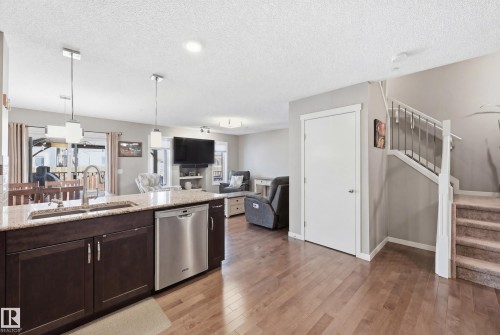 Kitchen with dishwasher, light stone counters, open floor plan, light wood-style flooring, and pendant lighting - 2031 Westerra Loop, Stony Plain, AB - Indoor Photo Showing Kitchen