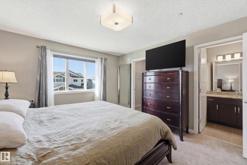 Bedroom with light carpet, a textured ceiling, connected bathroom, and a closet - 2031 Westerra Loop, Stony Plain, AB - Indoor Photo Showing Bedroom