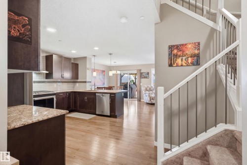 Kitchen with dark wood finish cabinetry, decorative light fixtures, light wood finished floors, stainless steel appliances, and backsplash - 2031 Westerra Loop, Stony Plain, AB - Indoor Photo Showing Kitchen With Upgraded Kitchen
