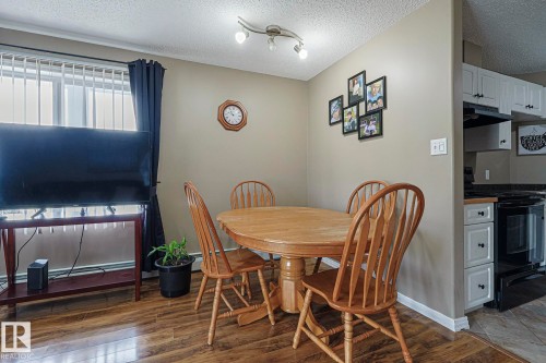 Dining space with a textured ceiling, dark wood finished floors, and baseboard heating - 314 5340 199 Street, Edmonton, AB - Indoor Photo Showing Dining Room