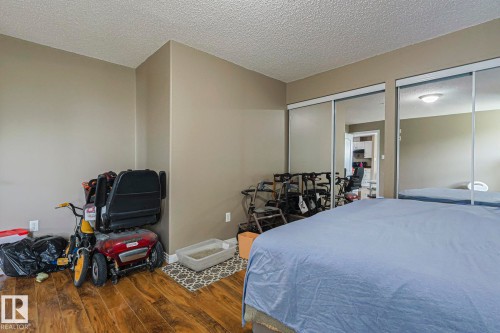 Bedroom with dark wood-style flooring, two closets, and a textured ceiling - 314 5340 199 Street, Edmonton, AB - Indoor Photo Showing Bedroom