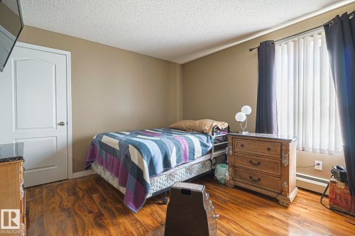 Bedroom with dark wood-style flooring, a textured ceiling, and baseboard heating - 314 5340 199 Street, Edmonton, AB - Indoor Photo Showing Bedroom