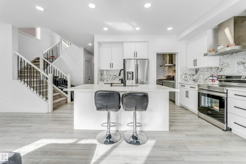 Kitchen with white cabinetry, stainless steel appliances, a kitchen bar, decorative backsplash, and recessed lighting - 2629 15A Avenue, Edmonton, AB - Indoor Photo Showing Kitchen With Upgraded Kitchen