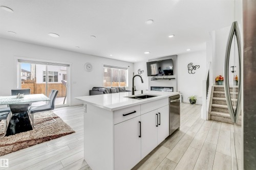 Kitchen with open floor plan, stainless steel appliances, a kitchen island with sink, white cabinetry, and light wood-style flooring - 2629 15A Avenue, Edmonton, AB - Indoor