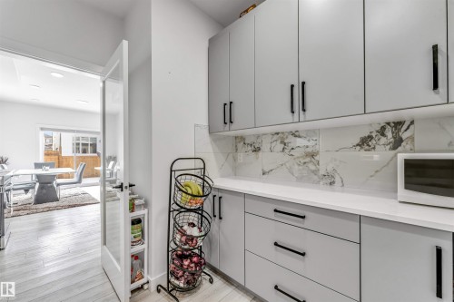 Detailed view of white microwave, wood finished floors, and backsplash - 2629 15A Avenue, Edmonton, AB - Indoor