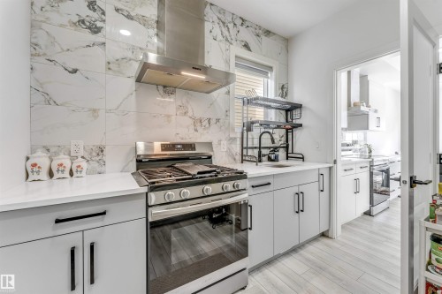 Kitchen featuring stainless steel gas range oven, stainless steel electric stove, open shelves, tasteful backsplash, and light wood-style flooring - 2629 15A Avenue, Edmonton, AB - Indoor Photo Showing Kitchen