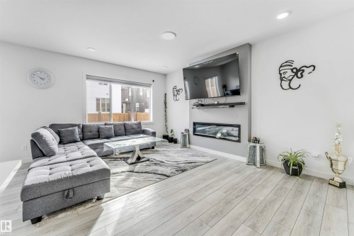 Living room with light wood finished floors, a glass covered fireplace, and recessed lighting - 2629 15A Avenue, Edmonton, AB - Indoor Photo Showing Living Room With Fireplace