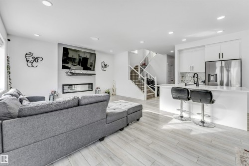 Living room with light wood-style floors, recessed lighting, and a glass covered fireplace - 2629 15A Avenue, Edmonton, AB - Indoor