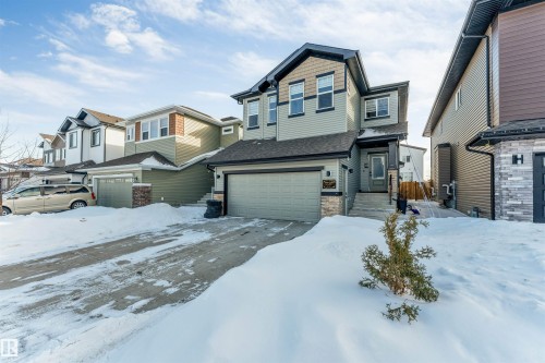 Craftsman-style house with a residential view, stone siding, an attached garage, and driveway - 2629 15A Avenue, Edmonton, AB - Outdoor With Facade