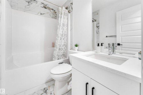 Full bath featuring vanity, shower / bath combination with curtain, and light marble finish floors - 2629 15A Avenue, Edmonton, AB - Indoor Photo Showing Bathroom