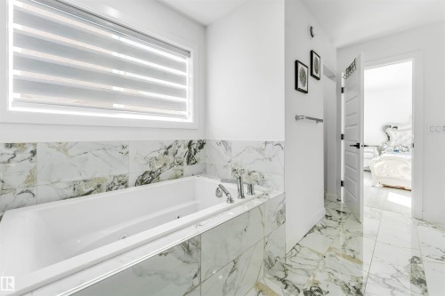 Ensuite bathroom featuring a jetted tub and light marble finish flooring - 2629 15A Avenue, Edmonton, AB - Indoor Photo Showing Bathroom