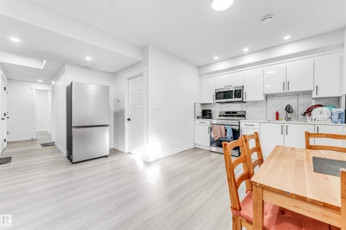 Kitchen with white cabinetry, stainless steel appliances, light countertops, light wood finished floors, and recessed lighting - 2629 15A Avenue, Edmonton, AB - Indoor