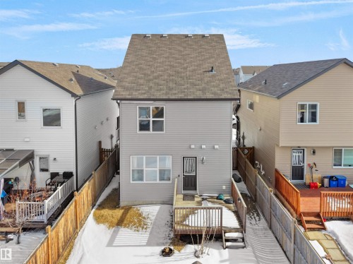 Rear view of property featuring a fenced backyard, a shingled roof, a wooden deck, and a residential view - 1708 62 Street, Edmonton, AB - Outdoor With Deck Patio Veranda