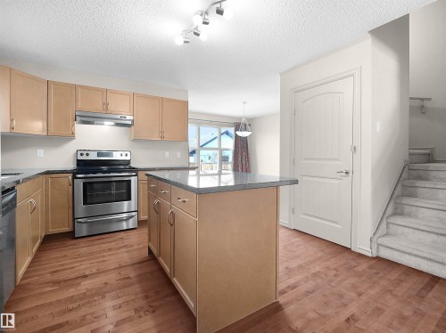 Kitchen featuring stainless steel appliances, a center island, light wood-style floors, a textured ceiling, and rail lighting - 1708 62 Street, Edmonton, AB - Indoor Photo Showing Kitchen