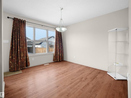 Unfurnished dining area with wood-type flooring and a textured ceiling - 1708 62 Street, Edmonton, AB - Indoor Photo Showing Other Room