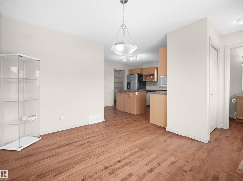 Kitchen with a breakfast bar area, stainless steel fridge, light wood-style flooring, dark stone counters, and a textured ceiling - 1708 62 Street, Edmonton, AB - Indoor Photo Showing Kitchen