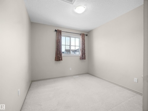 Unfurnished room featuring light colored carpet and a textured ceiling - 1708 62 Street, Edmonton, AB - Indoor Photo Showing Other Room