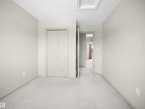 Unfurnished bedroom featuring light carpet, a textured ceiling, and a closet - 1708 62 Street, Edmonton, AB - Indoor Photo Showing Other Room