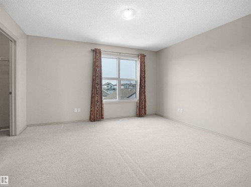 Unfurnished bedroom featuring light carpet and a textured ceiling - 1708 62 Street, Edmonton, AB - Indoor Photo Showing Other Room