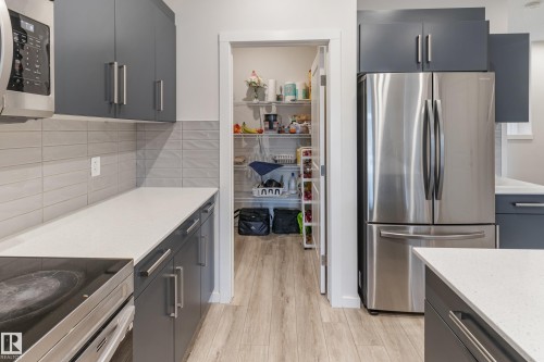 Kitchen featuring stainless steel appliances, light wood-style flooring, backsplash, and gray cabinetry - 304 36 Avenue, Edmonton, AB - Indoor Photo Showing Kitchen With Upgraded Kitchen