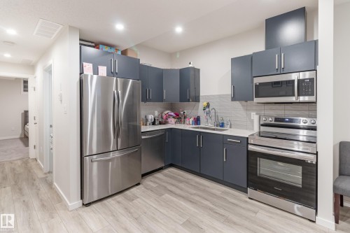 Kitchen with stainless steel appliances, light wood-style flooring, backsplash, recessed lighting, and light stone countertops - 304 36 Avenue, Edmonton, AB - Indoor Photo Showing Kitchen