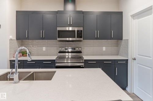 Kitchen with stainless steel appliances, light stone counters, decorative backsplash, and modern cabinets - 304 36 Avenue, Edmonton, AB - Indoor Photo Showing Kitchen With Double Sink With Upgraded Kitchen