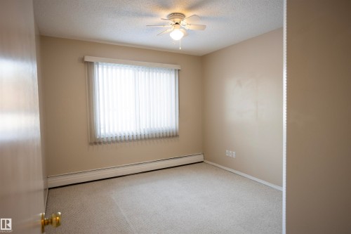 Spare room featuring a baseboard heating unit, carpet flooring, a textured ceiling, and a ceiling fan - 207 11465 41 Avenue, Edmonton, AB - Indoor Photo Showing Other Room