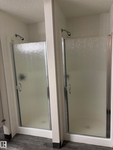 Dual shower stalls featuring frosted glass doors with chrome hardware - 207 11465 41 Avenue, Edmonton, AB - Indoor Photo Showing Bathroom