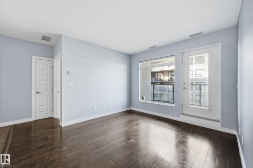 Spare room with dark wood-type flooring and baseboards - 511 5151 Windermere Boulevard, Edmonton, AB - Indoor Photo Showing Other Room
