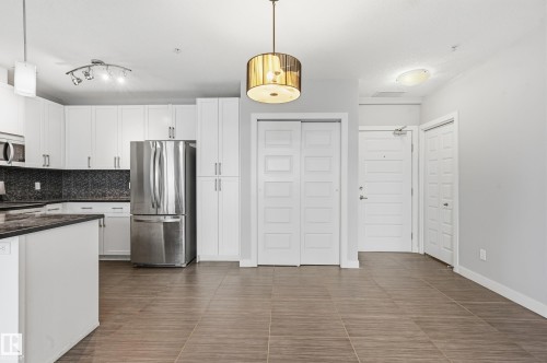 Kitchen featuring white cabinetry, stainless steel appliances, backsplash, and pendant lighting - 511 5151 Windermere Boulevard, Edmonton, AB - Indoor Photo Showing Kitchen With Upgraded Kitchen