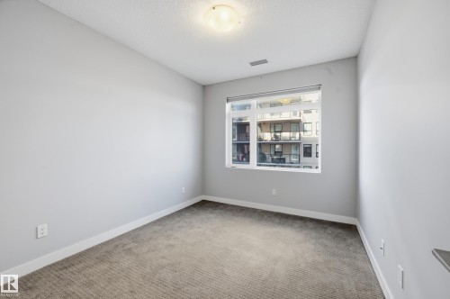 Unfurnished room featuring light colored carpet and a textured ceiling - 511 5151 Windermere Boulevard, Edmonton, AB - Indoor Photo Showing Other Room