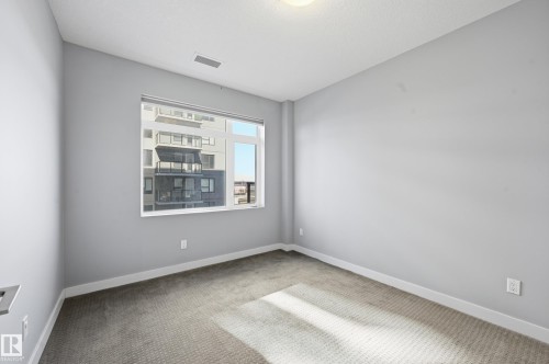 Spare room with light carpet and baseboards - 511 5151 Windermere Boulevard, Edmonton, AB - Indoor Photo Showing Other Room
