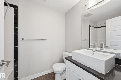 Bathroom with vanity, a textured ceiling, a shower, and dark wood finished floors - 511 5151 Windermere Boulevard, Edmonton, AB - Indoor Photo Showing Bathroom