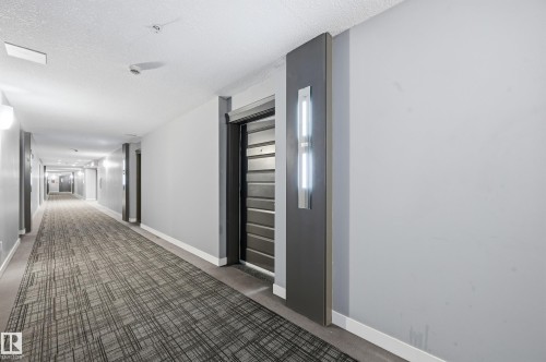 Hallway with a textured ceiling and dark carpet - 511 5151 Windermere Boulevard, Edmonton, AB - Indoor Photo Showing Other Room