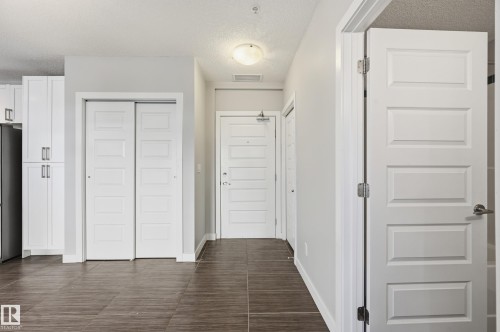 Hall with a textured ceiling and baseboards - 511 5151 Windermere Boulevard, Edmonton, AB - Indoor Photo Showing Other Room