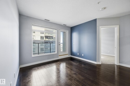 Spare room with baseboards and dark wood-type flooring - 511 5151 Windermere Boulevard, Edmonton, AB - Indoor Photo Showing Other Room