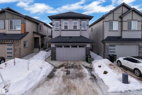 View of front facade featuring stone siding, roof with shingles, and driveway - 16812 48 Street Nw, Edmonton, AB - Outdoor With Facade
