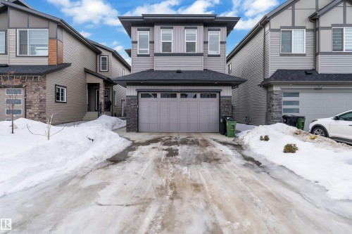 View of front of house with stone siding, an attached garage, and driveway - 16812 48 Street Nw, Edmonton, AB - Outdoor With Facade