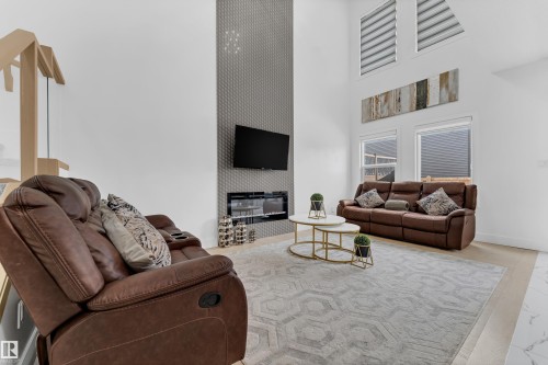 Living area with a high ceiling, a large fireplace, and an accent wall - 16812 48 Street Nw, Edmonton, AB - Indoor Photo Showing Living Room With Fireplace