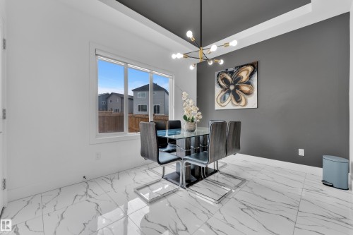 Dining space featuring suspended lighting, light marble finish flooring, and a tray ceiling - 16812 48 Street Nw, Edmonton, AB - Indoor