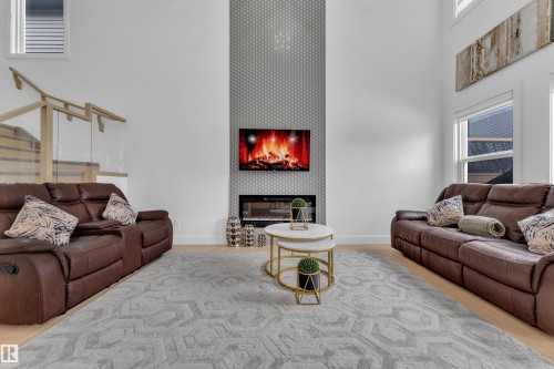 Living area with a high ceiling and a glass covered fireplace - 16812 48 Street Nw, Edmonton, AB - Indoor Photo Showing Living Room With Fireplace
