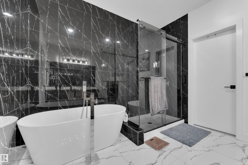 Bathroom featuring a soaking tub, a marble finish shower, marble finish floors, and tile walls - 16812 48 Street Nw, Edmonton, AB - Indoor Photo Showing Bathroom