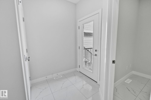 Doorway featuring marble look tiles and baseboards - 3524 41 Ave, Beaumont, AB - Indoor Photo Showing Other Room
