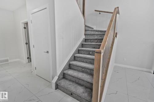 Staircase featuring baseboards and marble look tile flooring - 3524 41 Ave, Beaumont, AB - Indoor Photo Showing Other Room