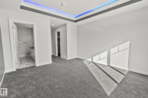 Unfurnished bedroom with a walk in closet, carpet flooring, a tray ceiling, and connected bathroom - 3524 41 Ave, Beaumont, AB - Indoor Photo Showing Other Room