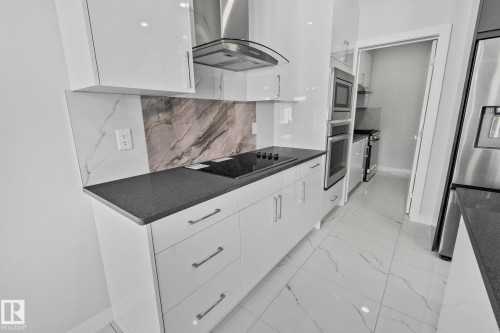 Kitchen featuring extractor fan, white cabinetry, stainless steel appliances, modern cabinets, and light marble finish flooring - 3524 41 Ave, Beaumont, AB - Indoor Photo Showing Kitchen With Upgraded Kitchen