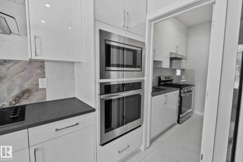 Kitchen with backsplash, white cabinetry, stainless steel appliances, and extractor fan - 3524 41 Ave, Beaumont, AB - Indoor Photo Showing Kitchen