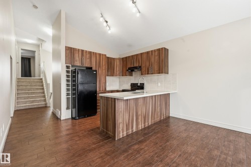 Kitchen featuring wood finish cabinetry, light countertops, black appliances, vaulted ceiling, and dark wood-style flooring - 1346 Cunningham Drive W, Edmonton, AB - Indoor Photo Showing Kitchen